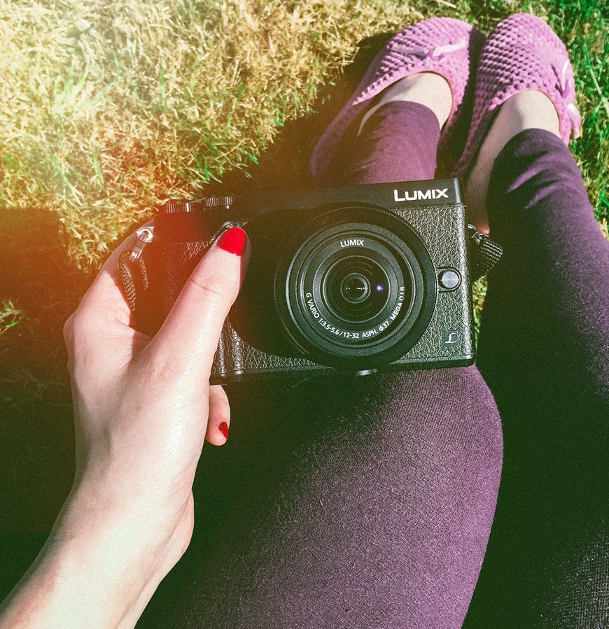 A woman holding a camera in the grass.