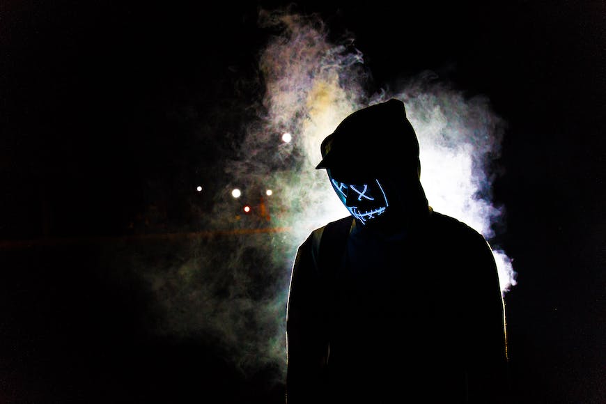 A person in a hoodie standing in front of smoke.