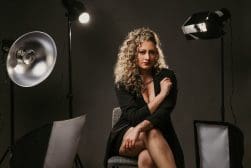 A woman sitting on a chair in front of lighting equipment.