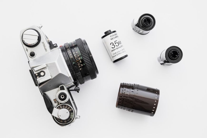 A camera, film, and a roll of film on a white surface.