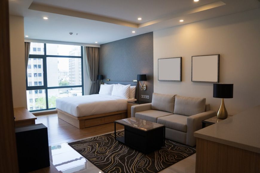 A modern hotel room with a bed, couch and tv.