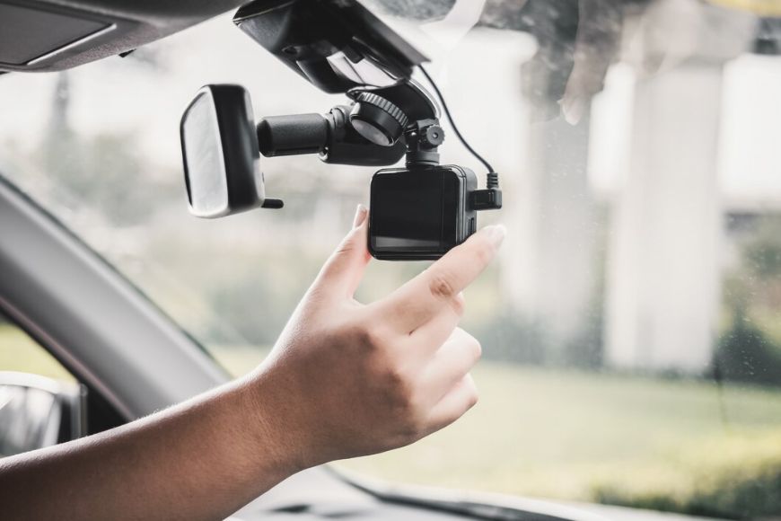 A person is holding up a camera in a car.