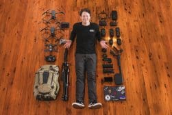 A man laying on a wooden floor with a lot of camera equipment.