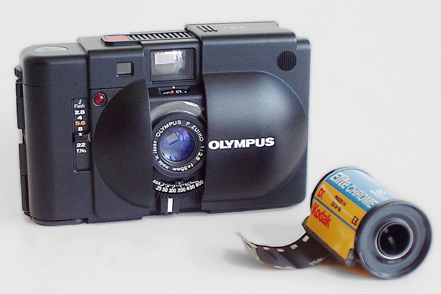 A camera with a roll of film next to it.