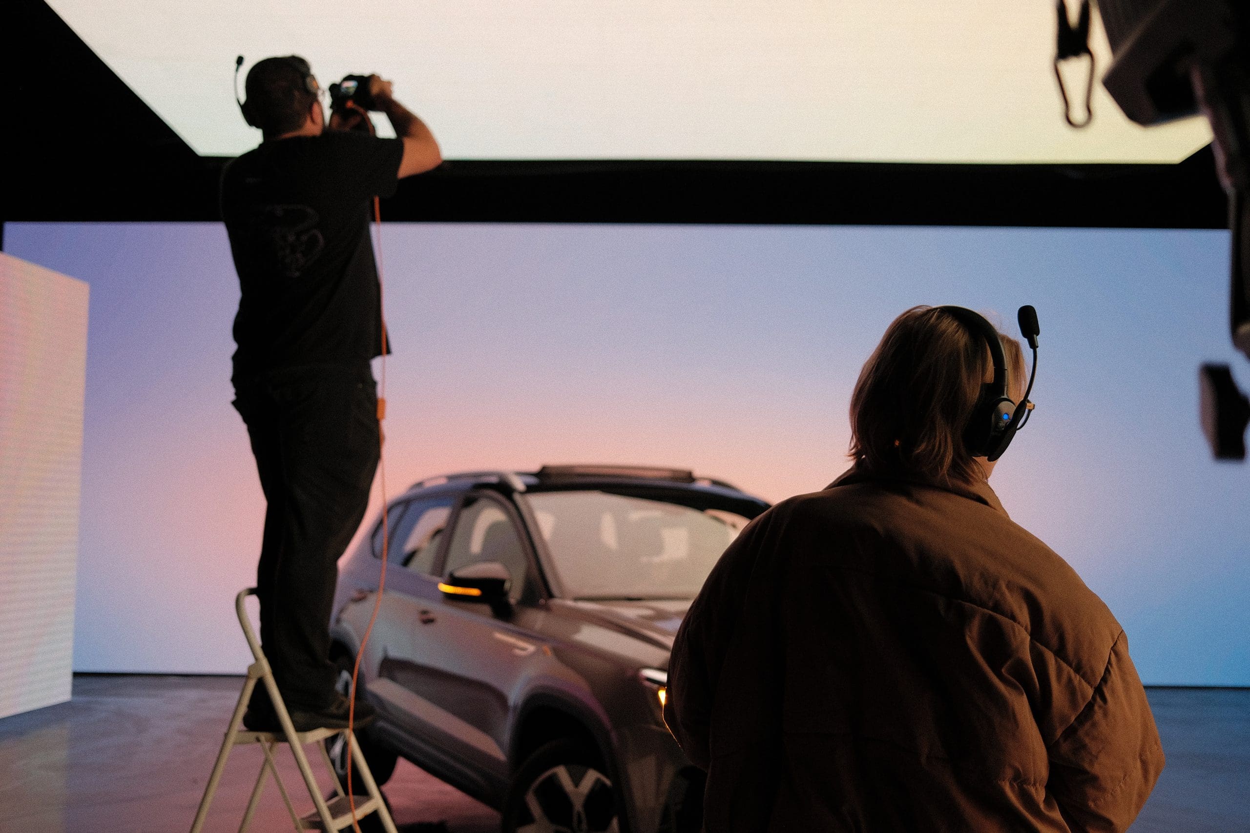 A man is taking a picture of a car in a studio.