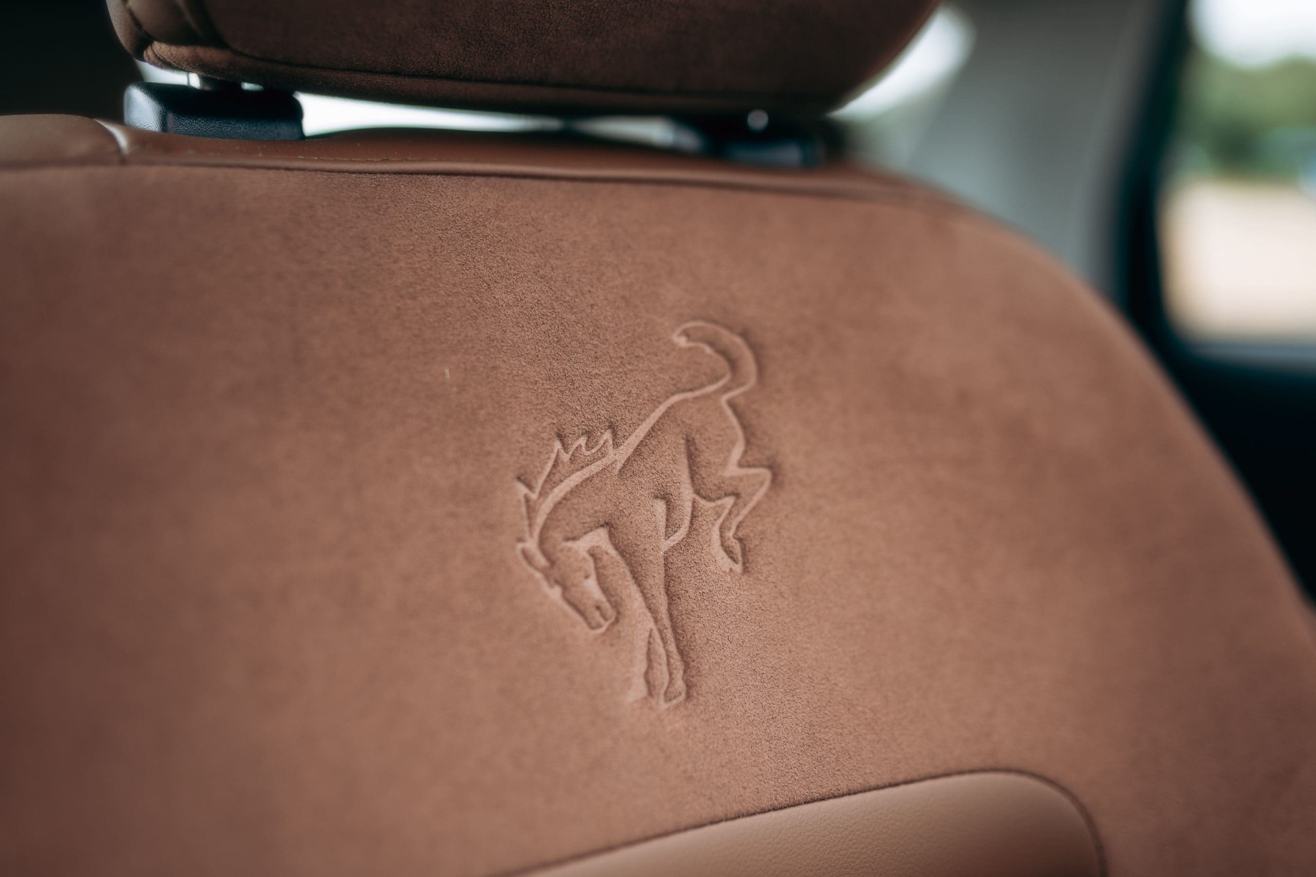 The back seat of a car with a horse embroidered on it.