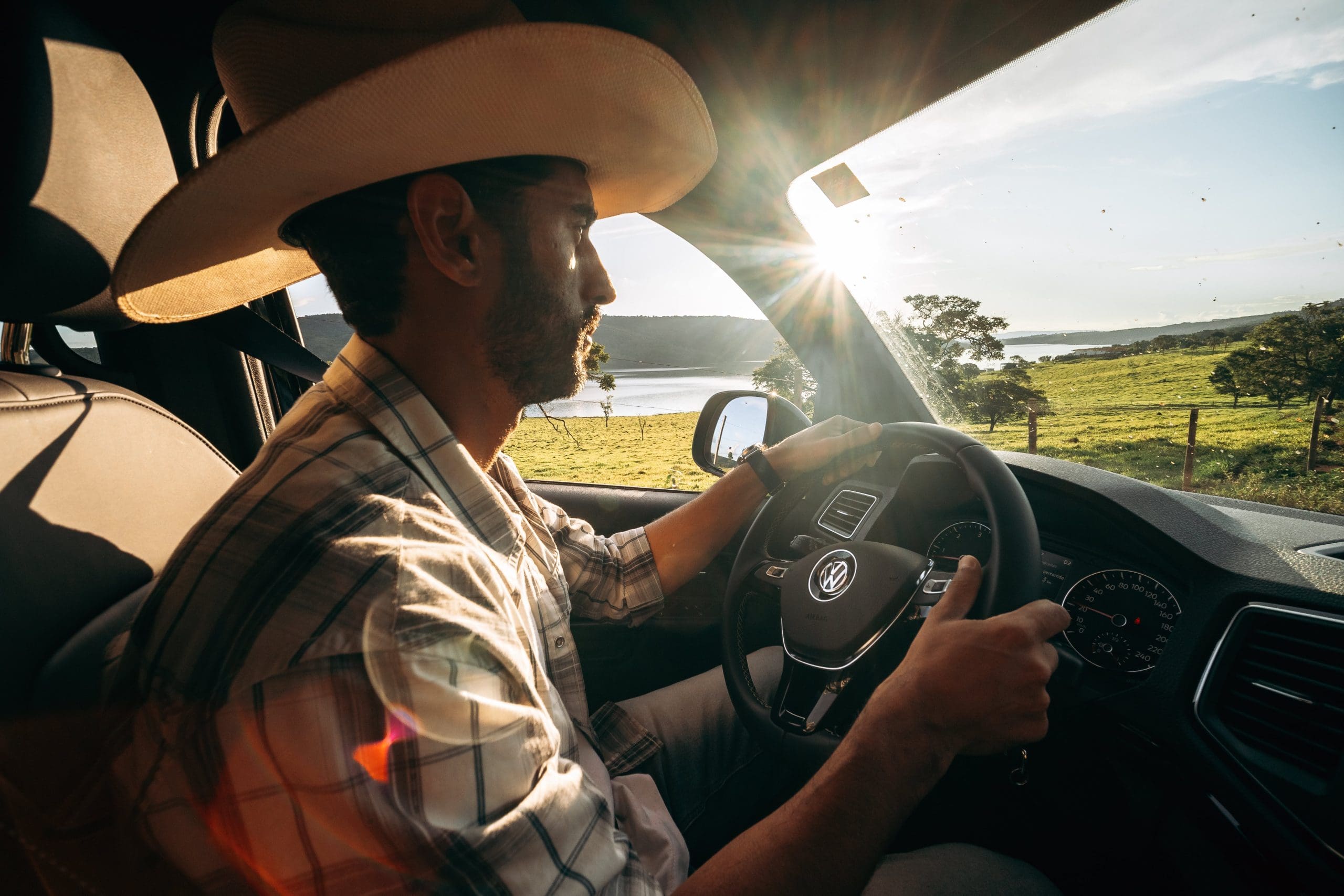 A man in a cowboy hat driving a car.