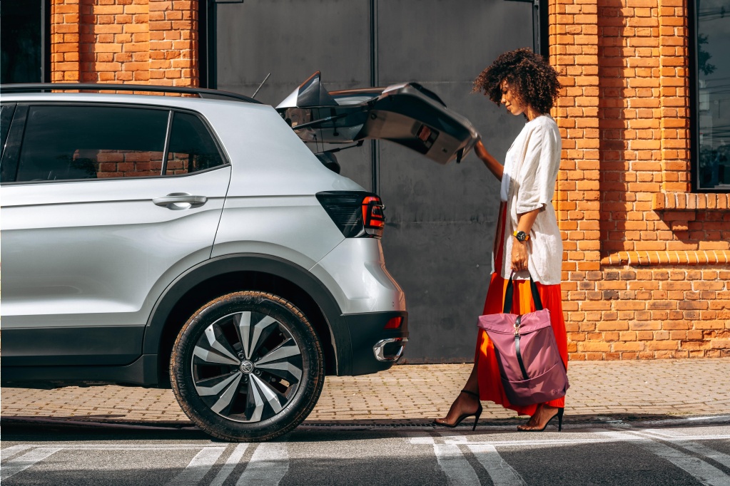 A woman opens the trunk of a volkswagen tiguan.