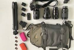 A backpack with camera equipment laid out on a table.