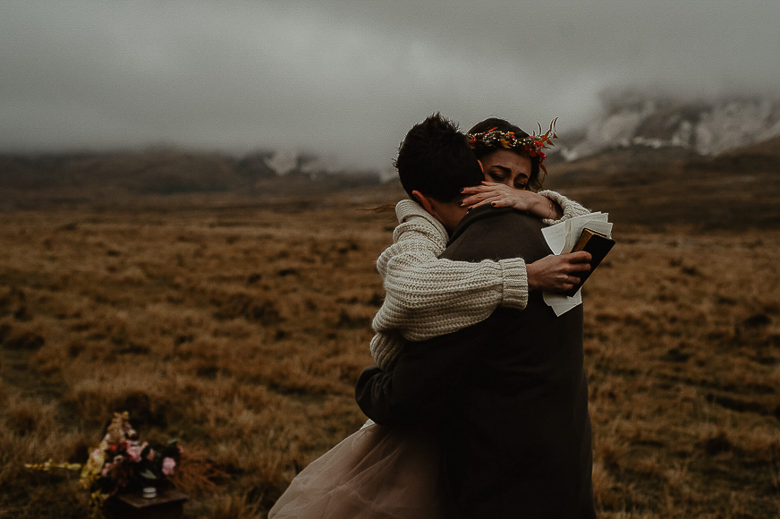 A bride and groom hugging in the middle of a field.