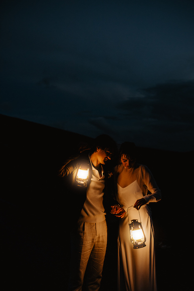 A bride and groom holding lanterns in the dark.