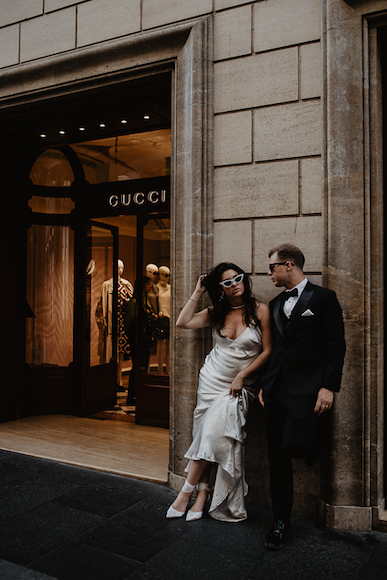 A bride and groom pose in front of a gucci store.