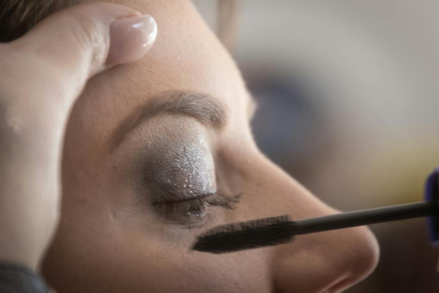 A woman is applying mascara to her eye.