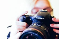 A woman is taking a picture with a canon dslr camera.