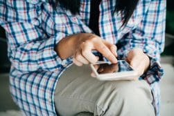 A woman in a plaid shirt is using a cell phone.