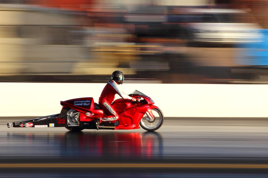 A person riding a red motorcycle on a track.