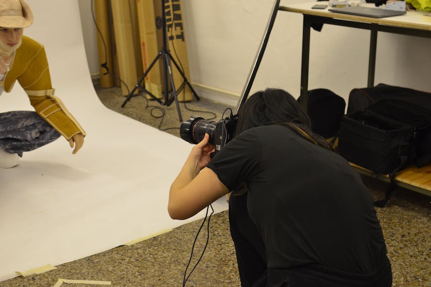 A woman is taking pictures of a mannequin in a studio.