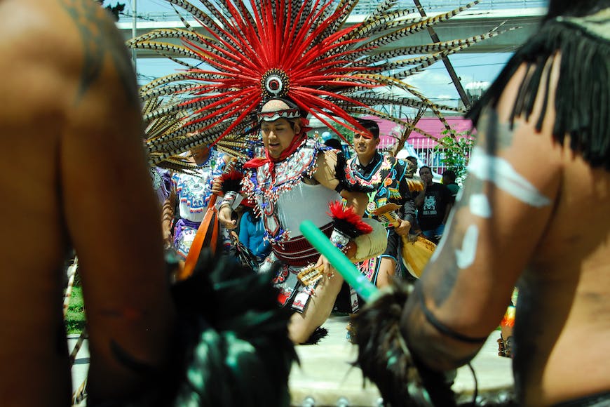 A group of indian dancers with feathered headdresses.