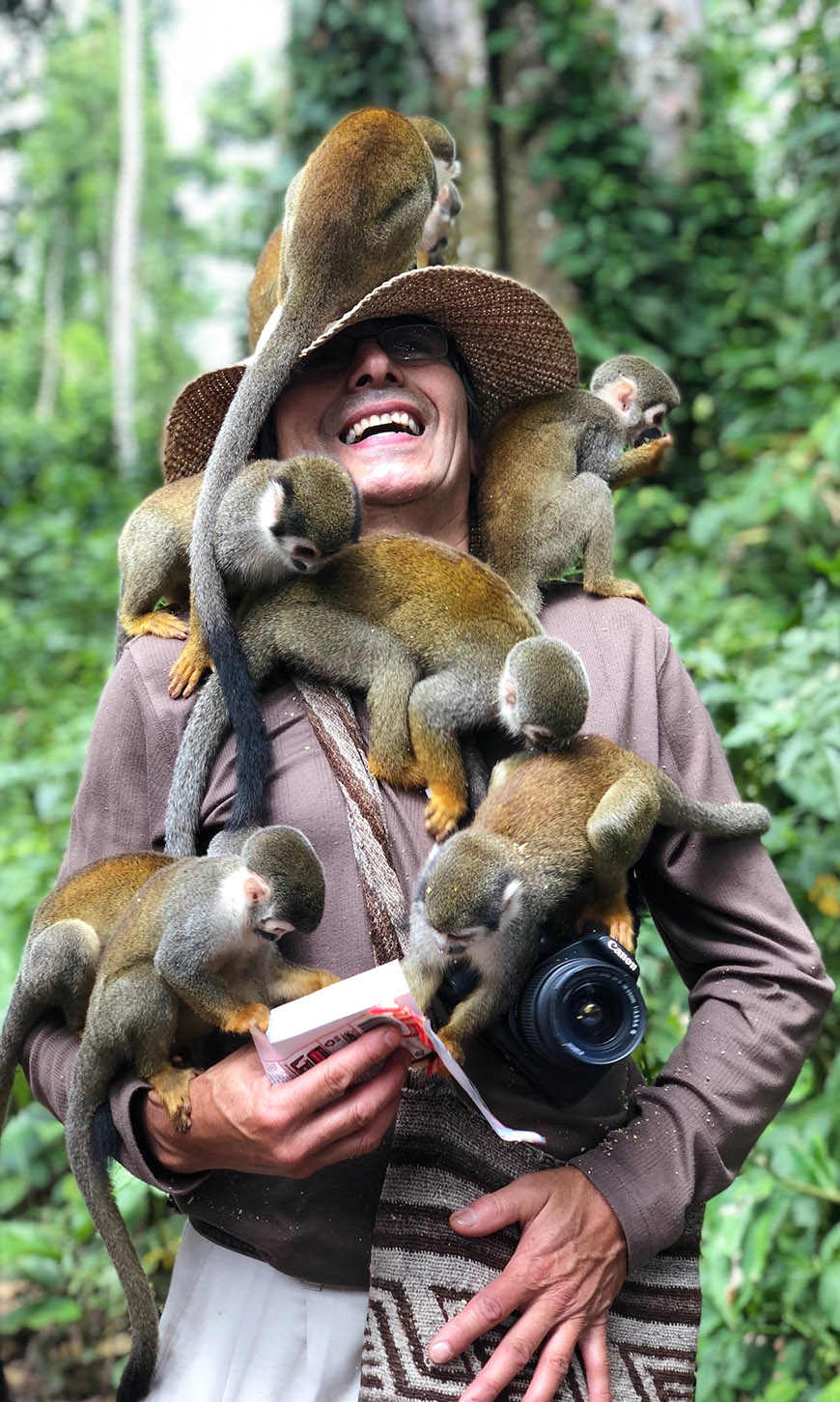 A woman in a hat with monkeys on her shoulders.