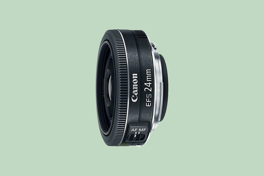 Black canon ef-s 24mm camera lens against a plain background.