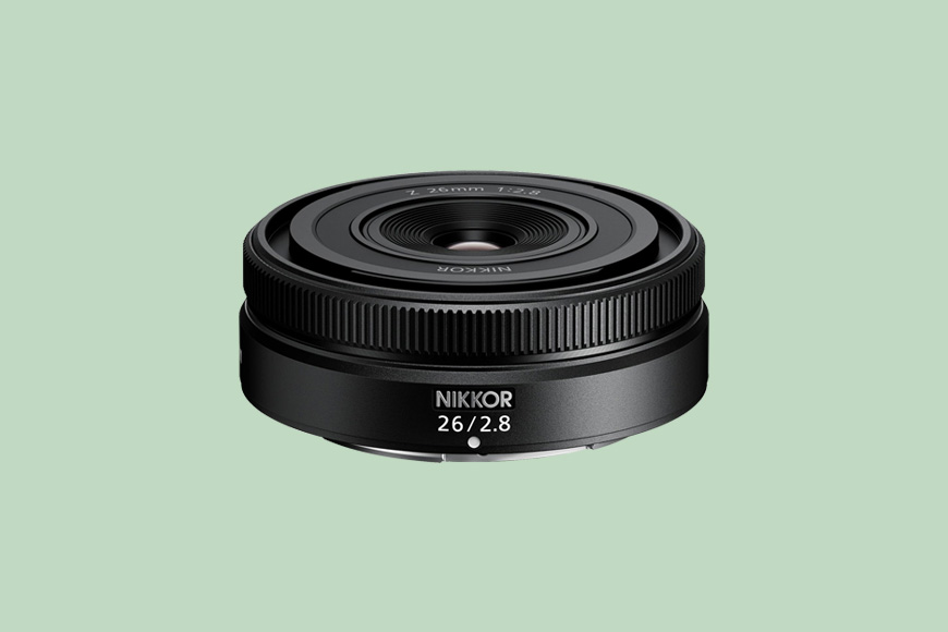 Nikon nikkor 26mm f/2.8 camera lens against a plain background.