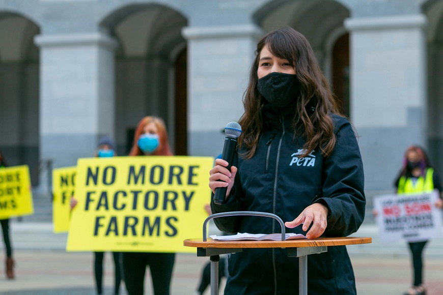 A woman holding a sign saying no more factory farms in san francisco.