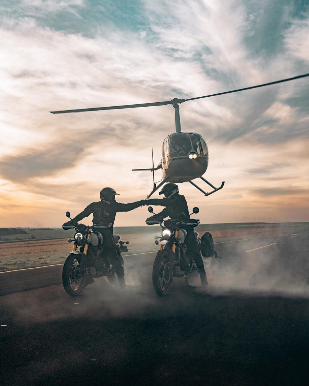 Two motorcycles on the road next to a helicopter.