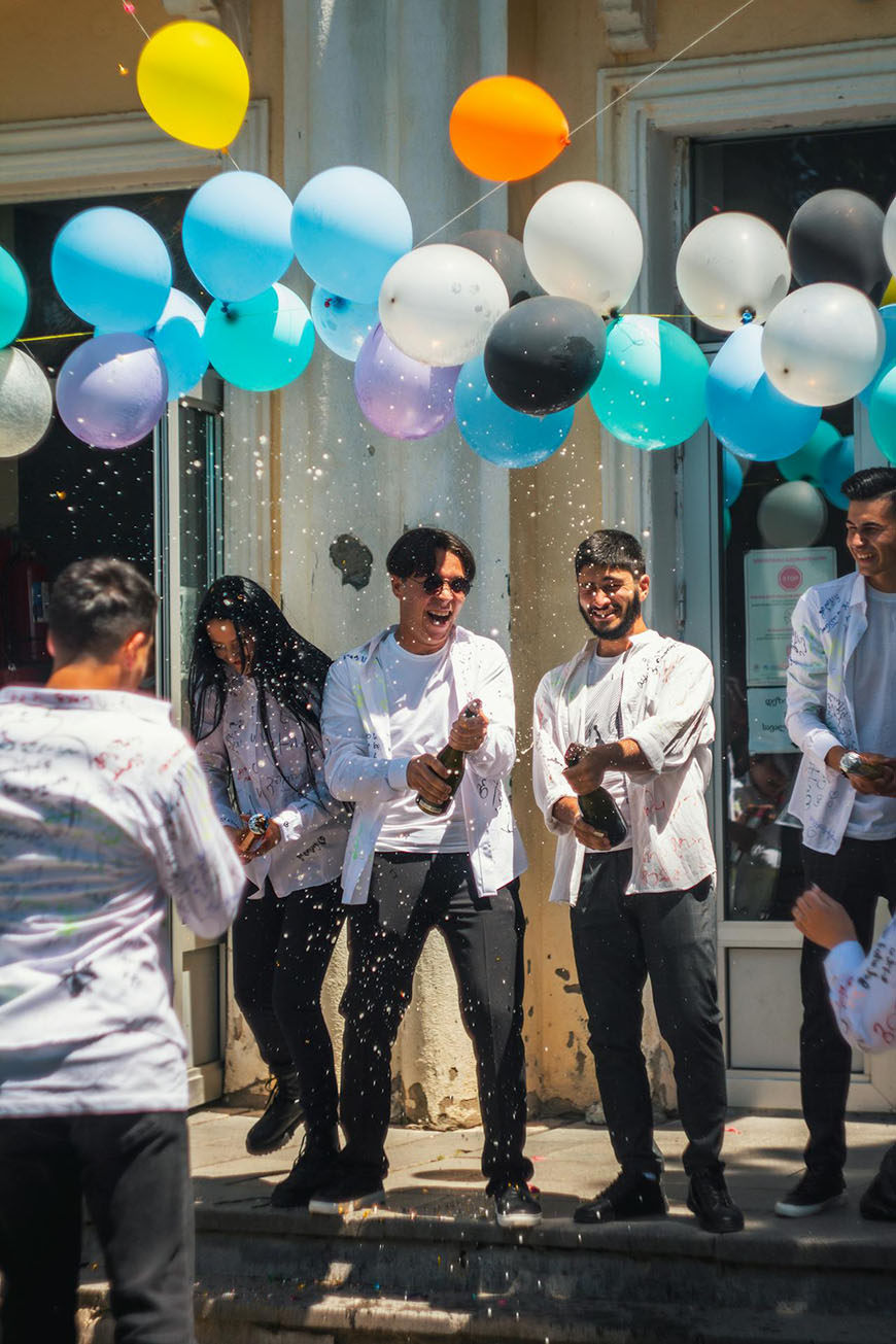 A group of men holding balloons in front of a building.