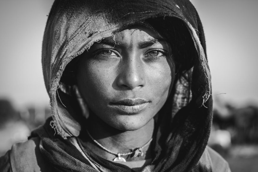 A black and white photo of a woman wearing a hood.
