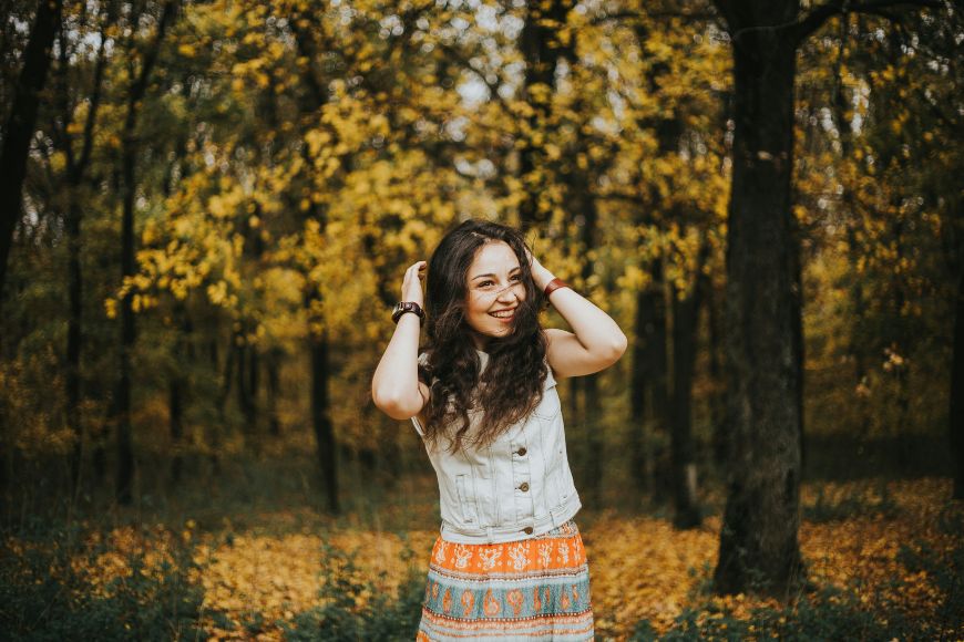 A young woman in an orange skirt standing in a forest.