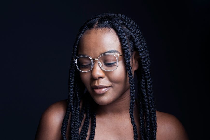A woman with braids and glasses is posing for a photo.