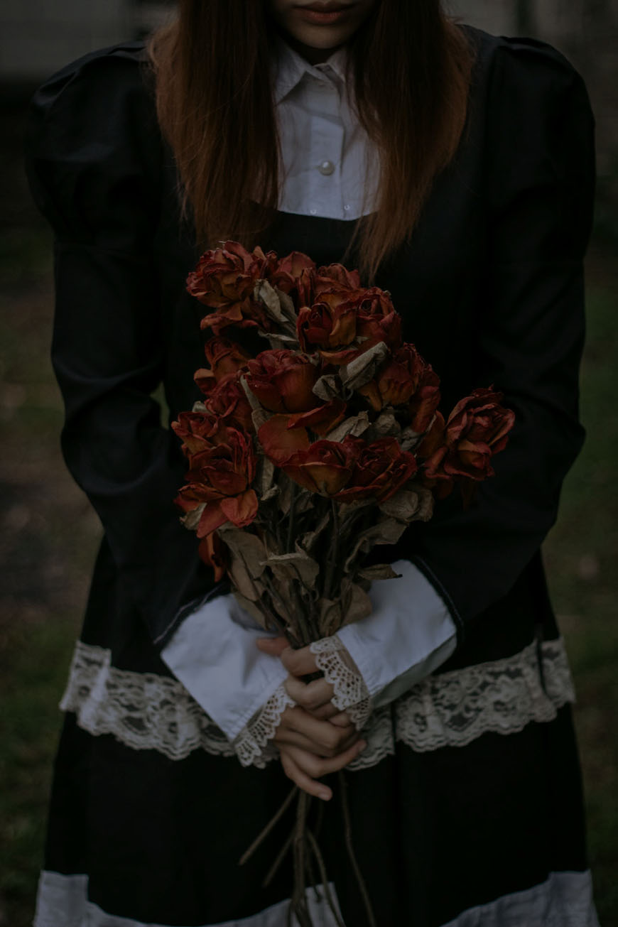 A girl in a black dress holding a bunch of roses.