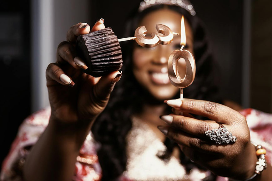 A woman holding up a cupcake with a number on it.
