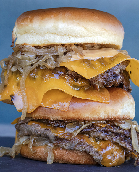 A stack of hamburgers with cheese and onions.