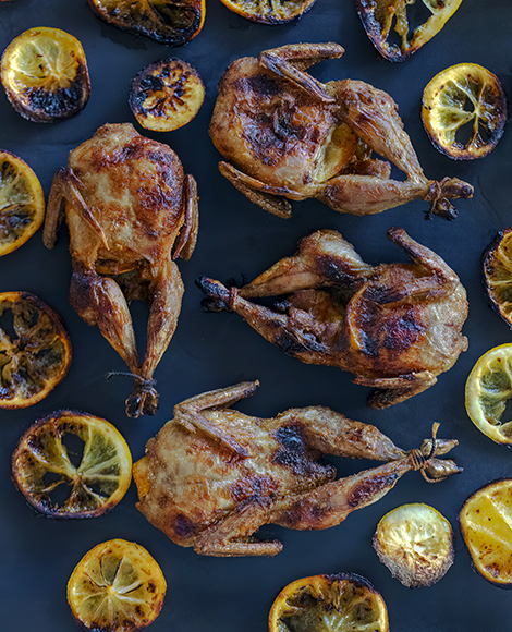 Roasted chicken with lemon slices on a baking sheet.