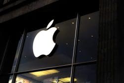 An apple logo is seen in the window of a store.