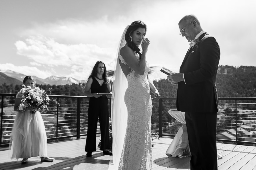 A bride and groom exchange vows on a balcony overlooking the mountains.