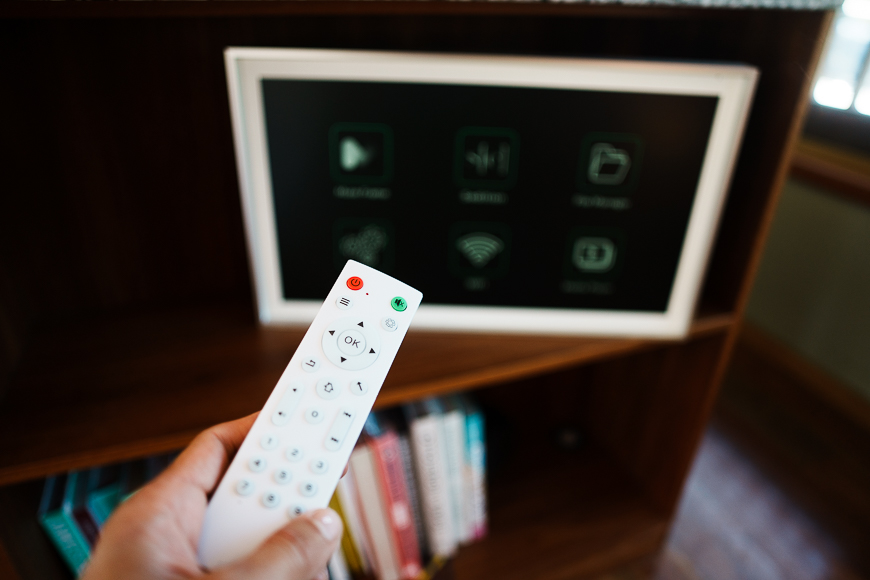 A person holding a remote control in front of a television.