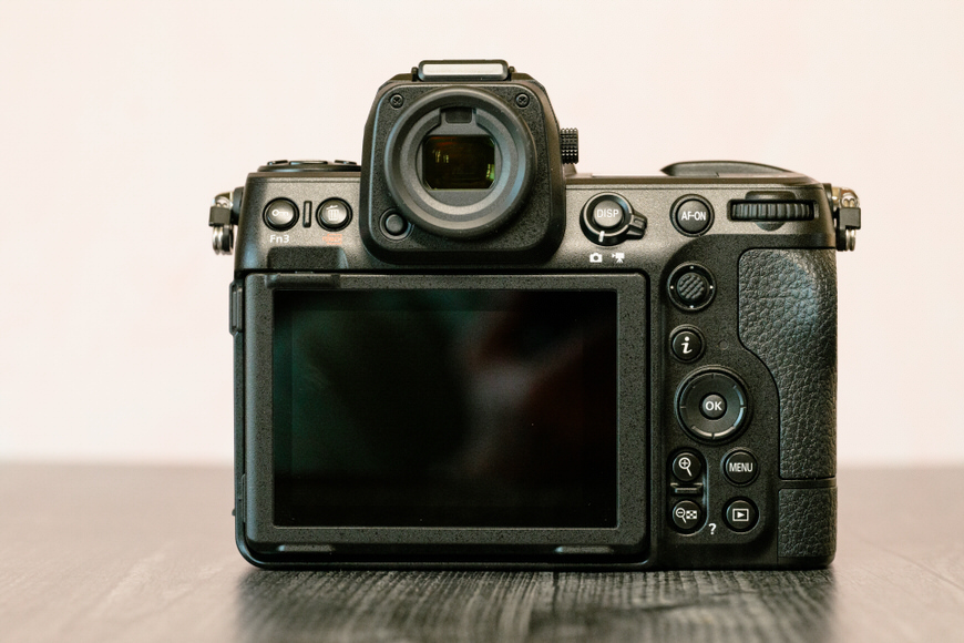 Black mirrorless camera with an articulating screen against a neutral background.