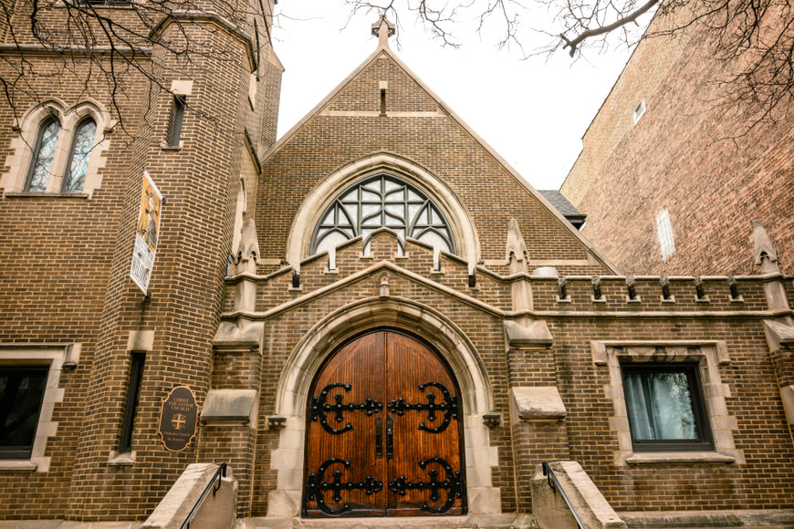 Gothic-style church entrance with a large wooden door and ornate stonework.