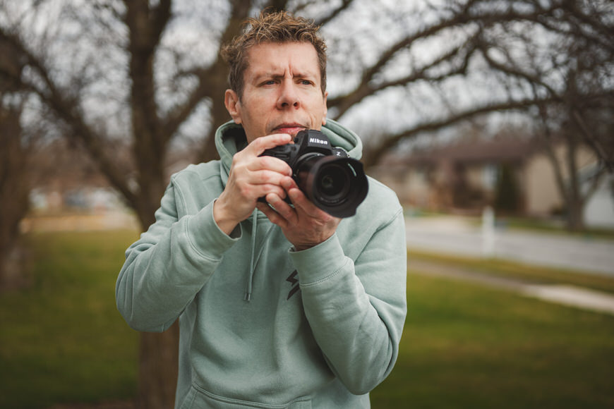 A focused person taking a photograph with a dslr camera outdoors.