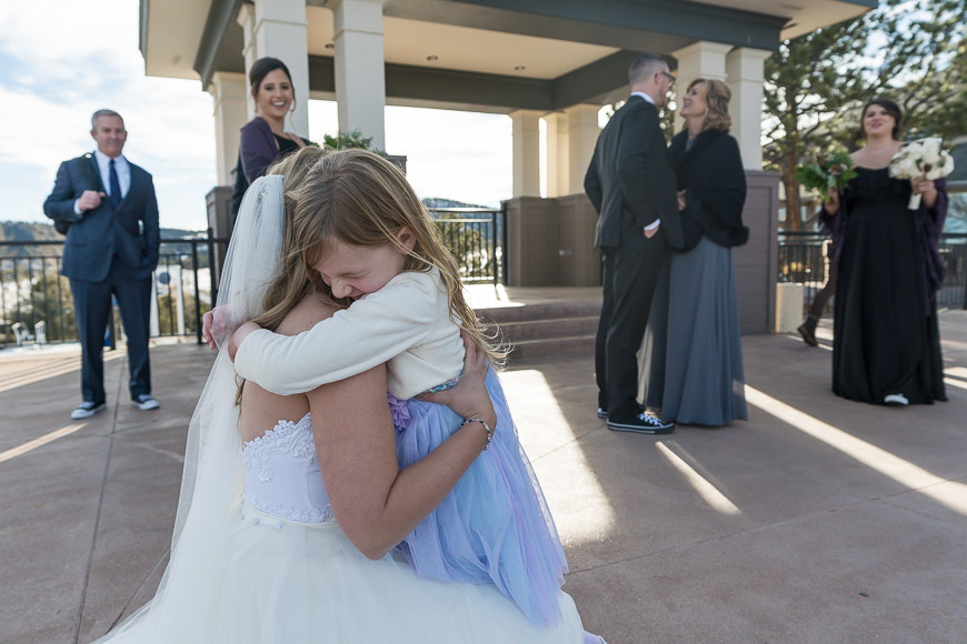 A little girl is hugging a bride during her wedding ceremony.