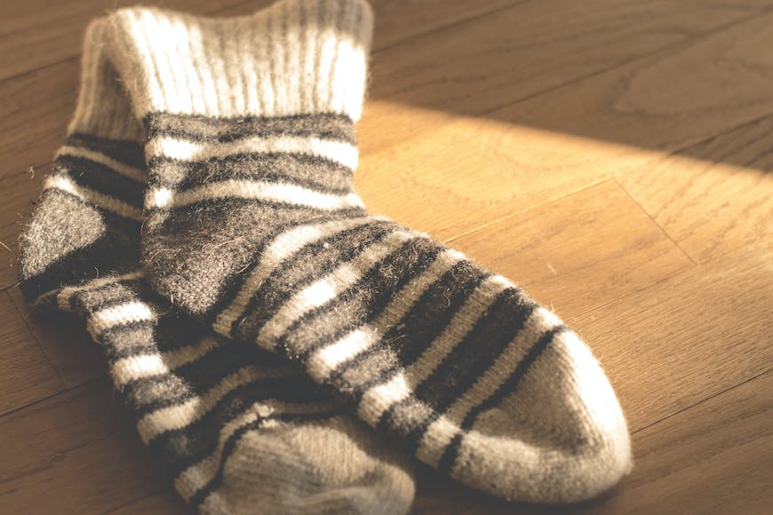 A pair of black and white striped socks on a wooden floor.