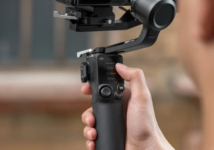 A person holding a handheld gimbal stabilizer for a camera.