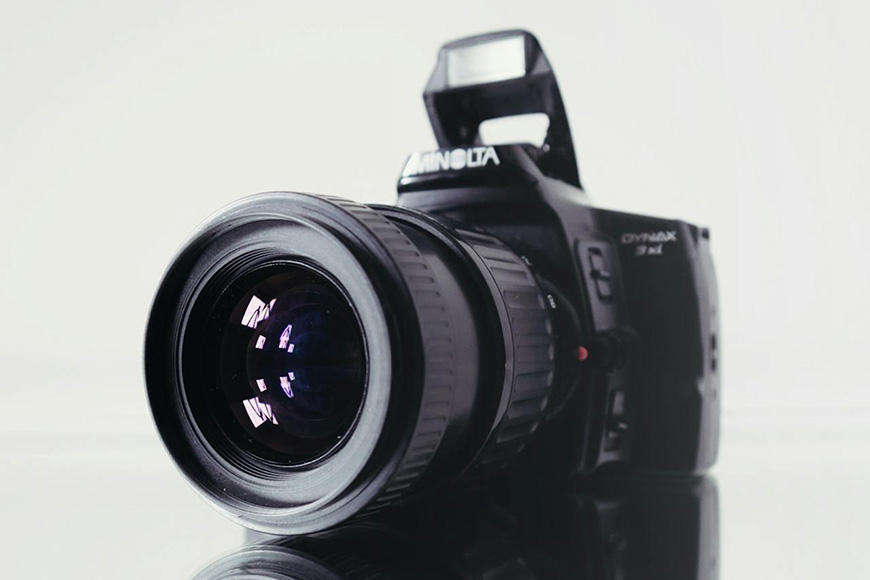 A minolta dynax slr camera with a front-facing lens on a white background.