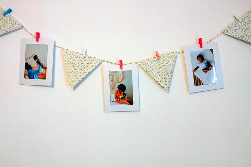 Three photographs hanging from a string against a white wall, secured by colorful clothespins.