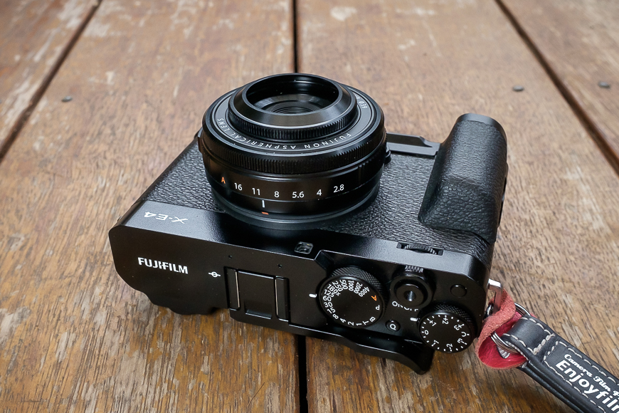 A fujifilm x-pro2 camera with a prime lens on a wooden surface.