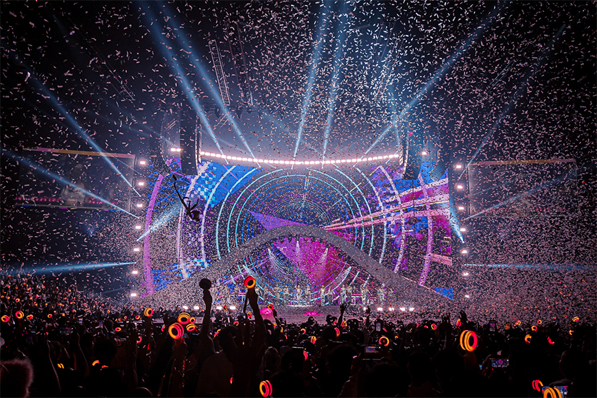 Colorful concert stage with a dynamic light show and confetti falling onto an enthusiastic audience.