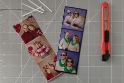 Two strips of photo booth images featuring a couple posing with props, alongside a craft knife and pieces of white sticks on a cutting mat with grid lines.
