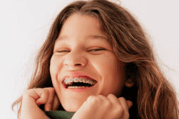 Girl with braces smiling warmly.